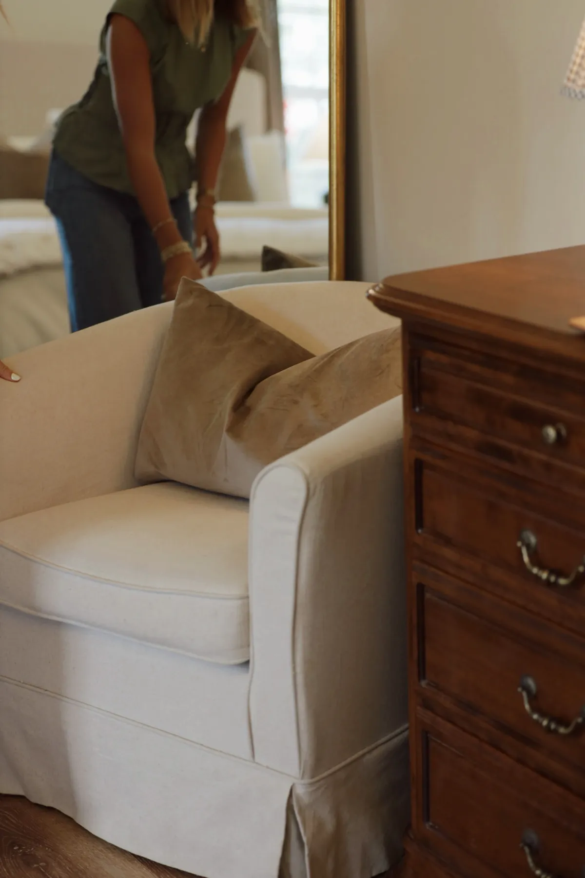 Slipcovered armchair styled beside an antique wood dresser during a home install