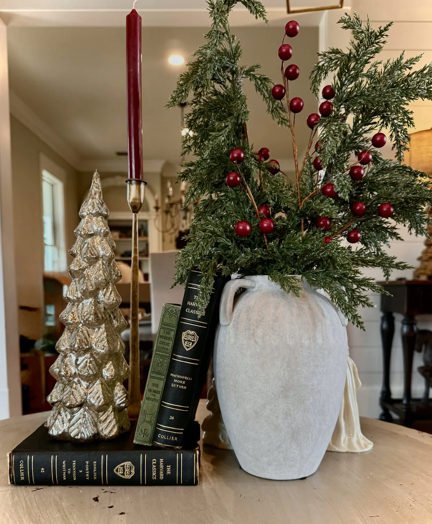 Holiday arrangement of cedar and red berries with tapers and a glass tree