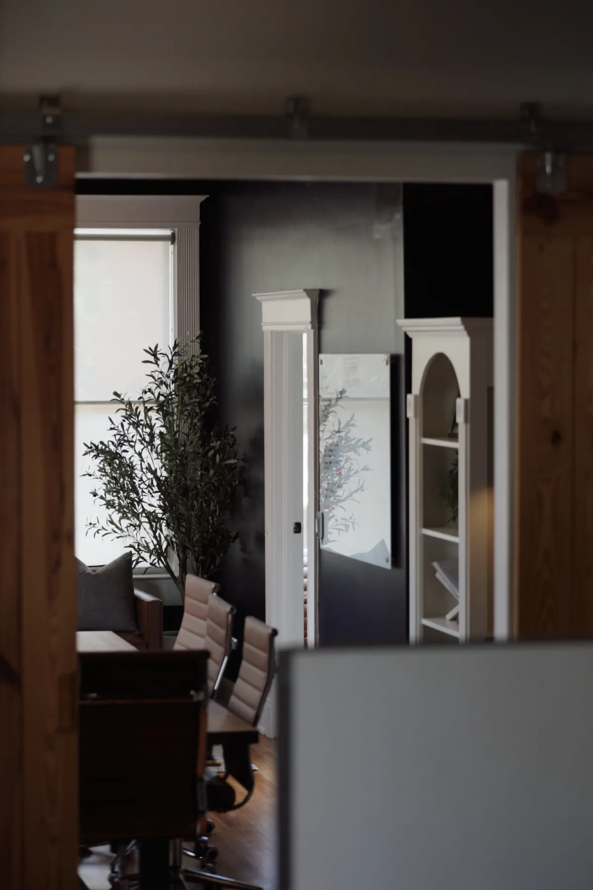 View through a sliding barn door into a softly lit office workspace