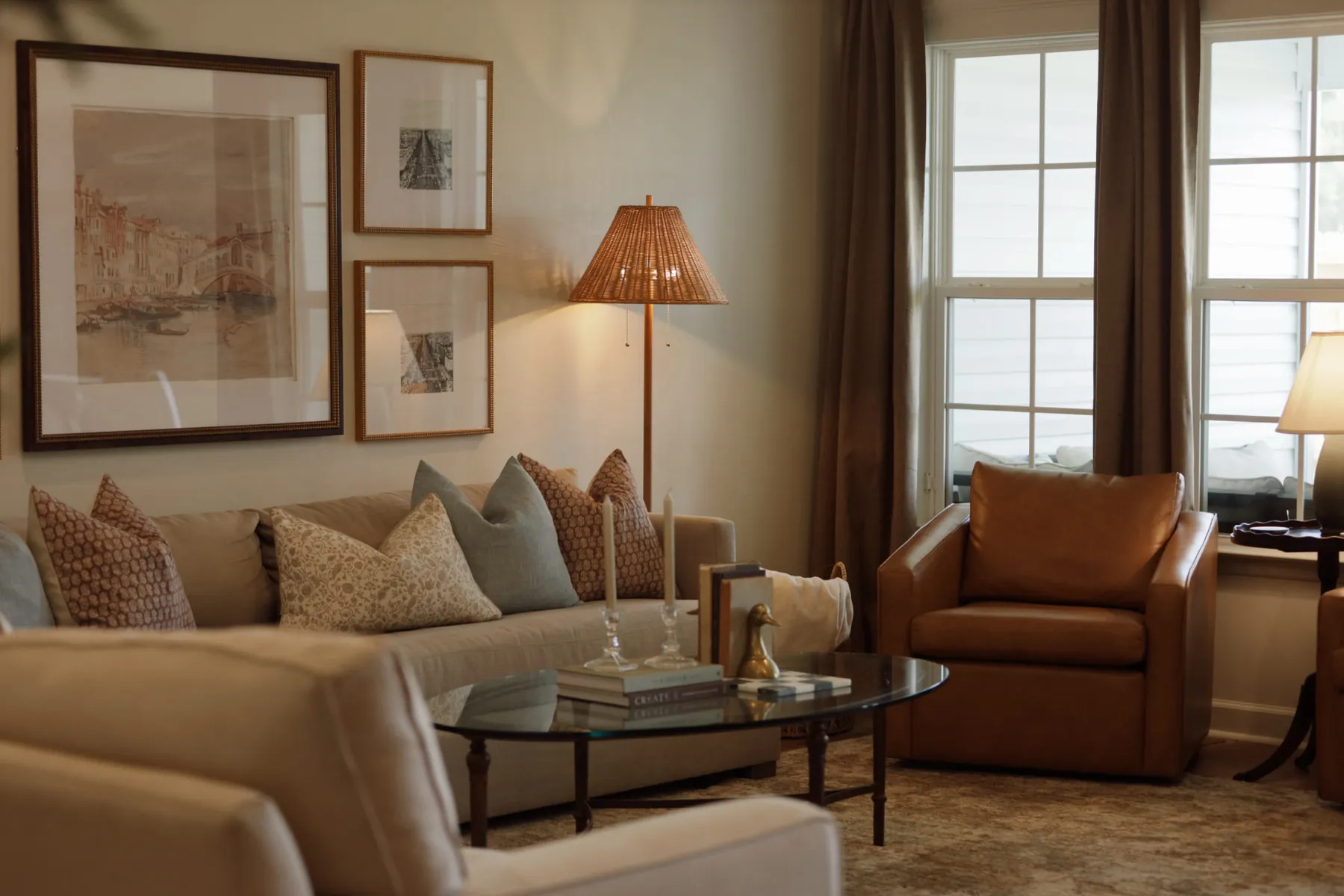 Living room with a framed art wall, pillowed sofa and pleated floor lamp