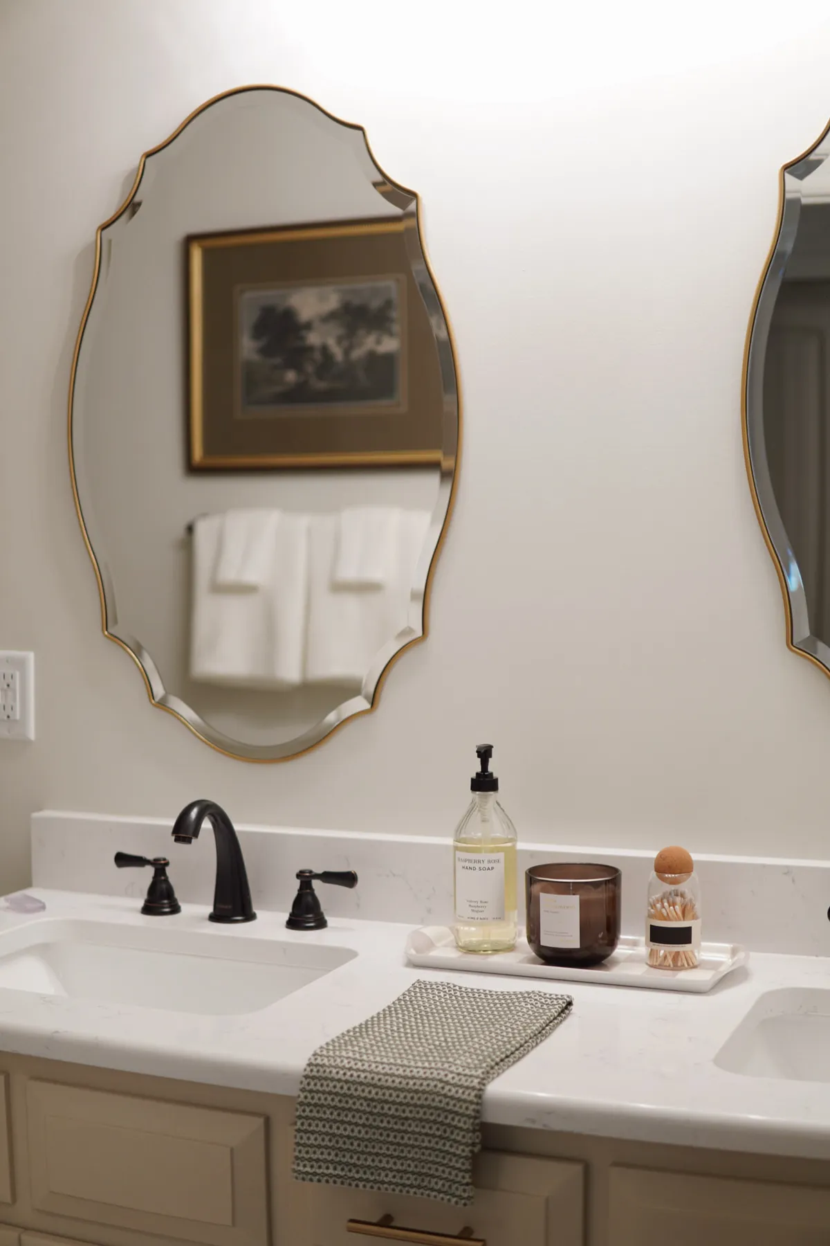 Bathroom vanity with a scalloped gold mirror, white counter and folded towels