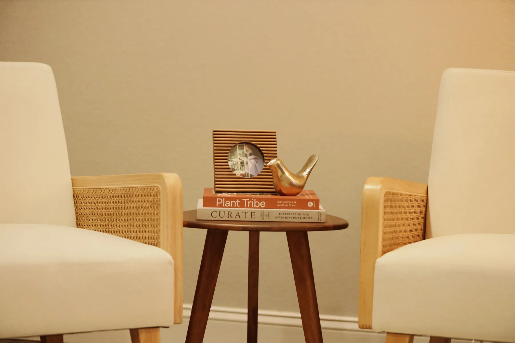 Waiting area with two cream chairs and a small round wood side table