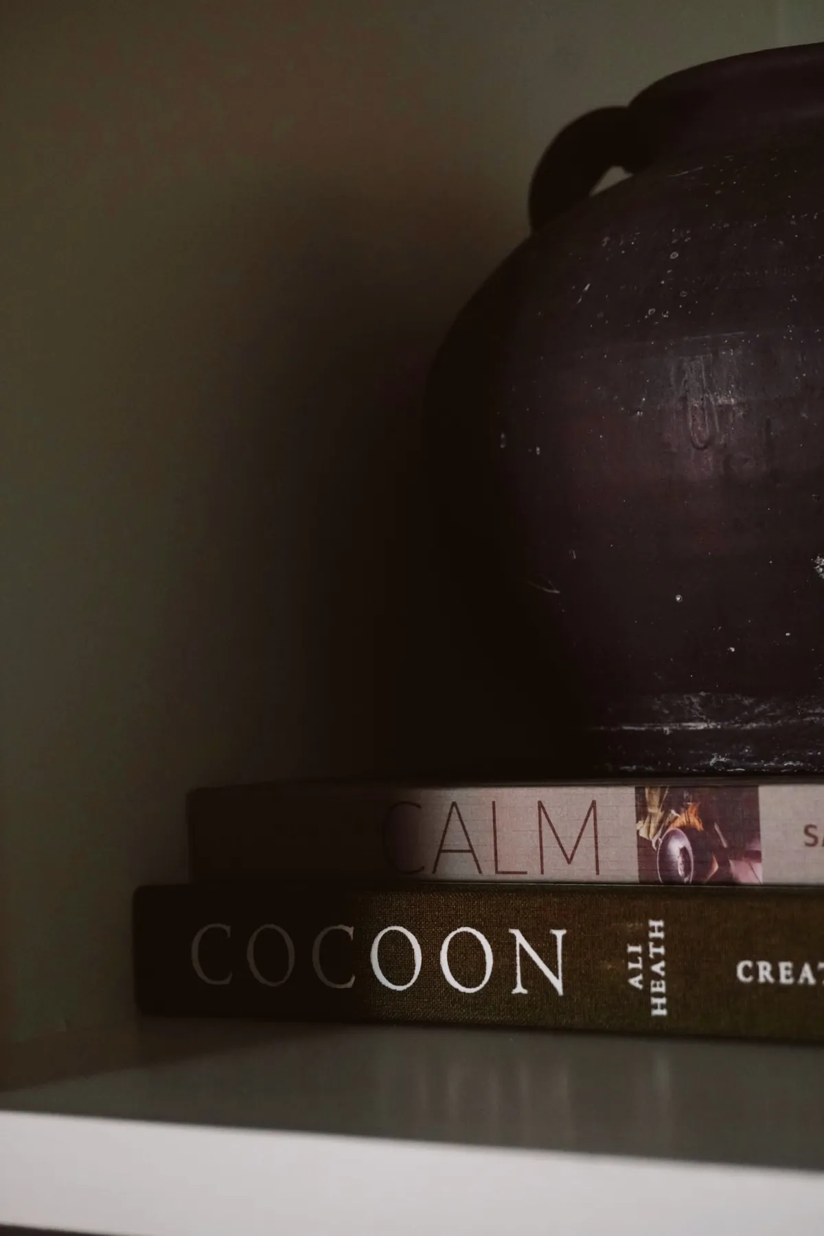Dark ceramic vessel resting on a stack of design books