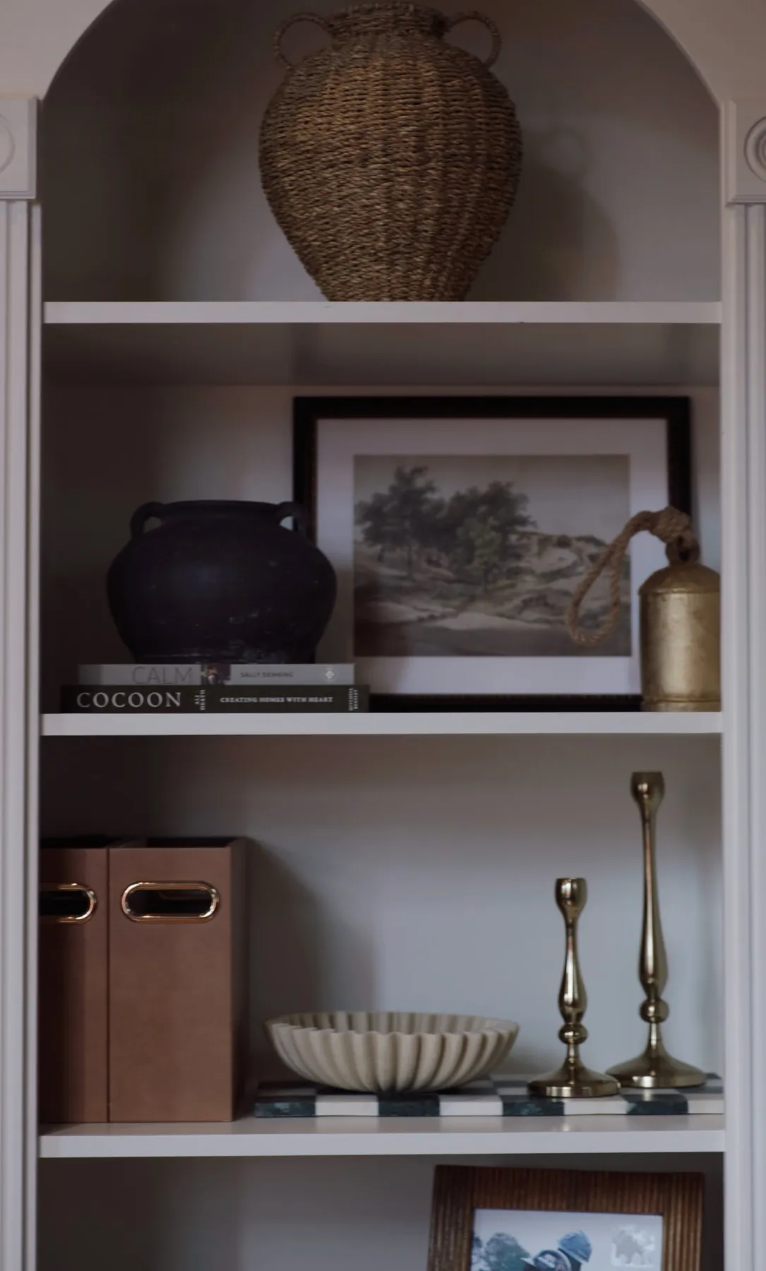 Built-in office shelving styled with a woven basket, art and brass candlesticks