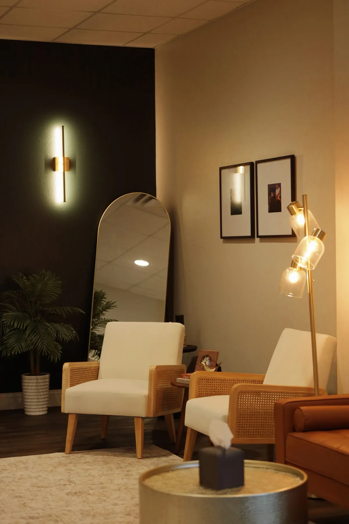 Reception seating with cane chairs, an arched mirror and a backlit wall sconce