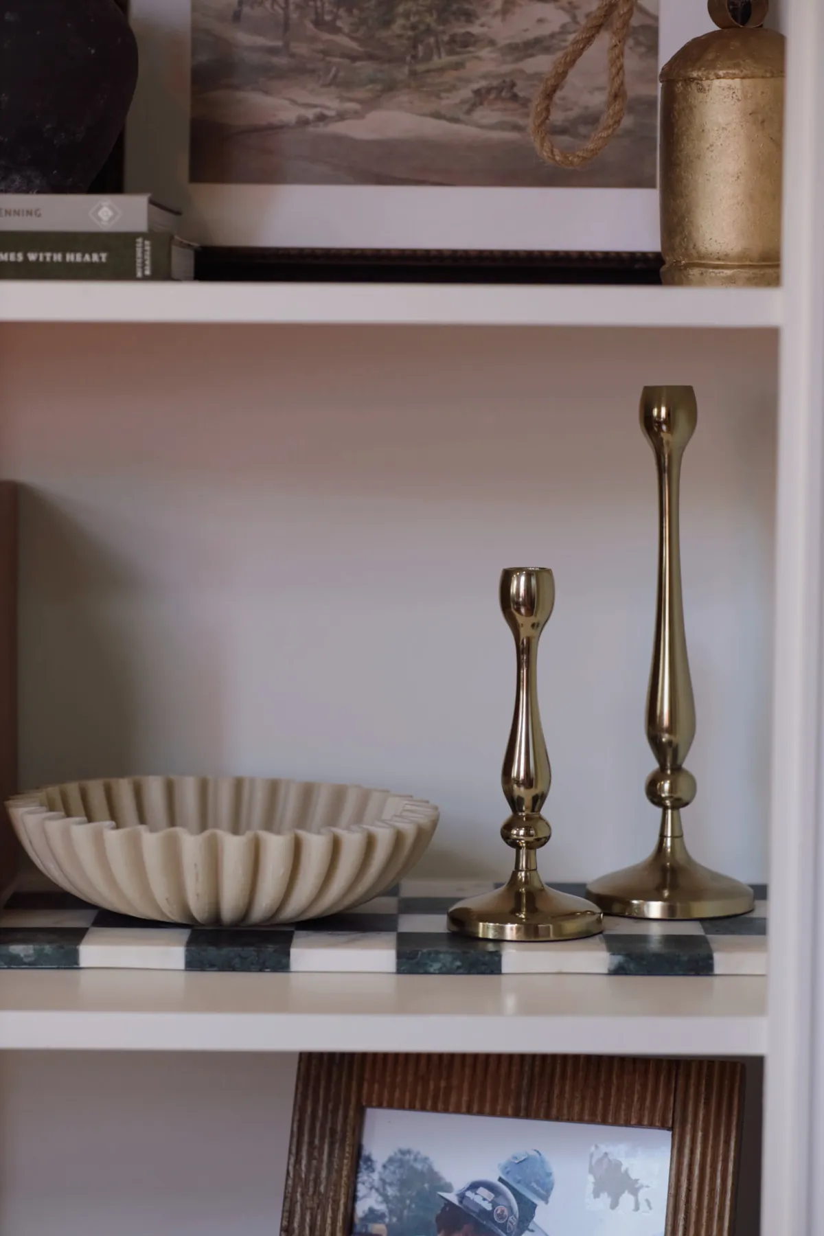 White shelf styled with a scalloped bowl and brass candlesticks