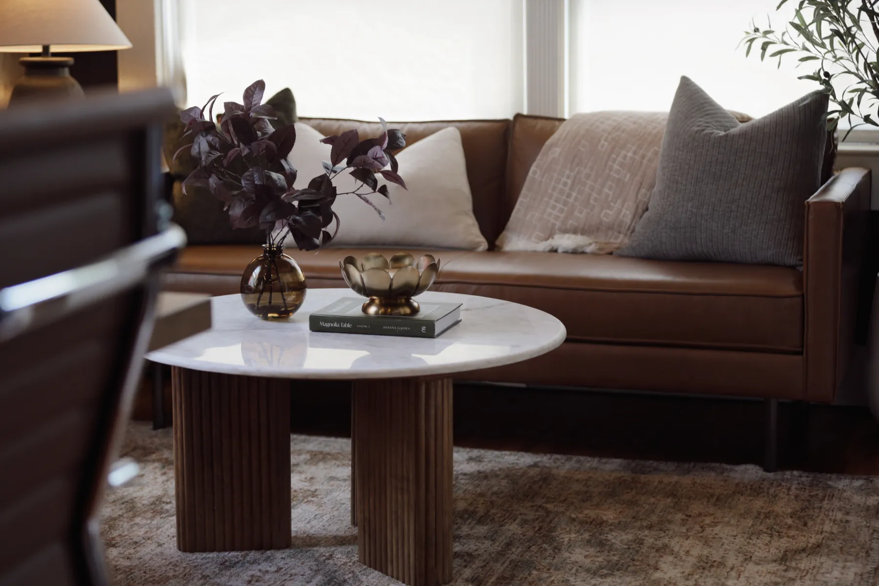 Office lounge with a leather sofa, marble coffee table and floral arrangement